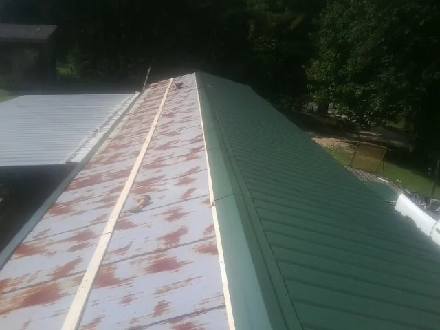 Old rusted panels beside newly installed green metal roofing — Wind Damage Roof Repair by Roofing Brothers in West Wardsboro