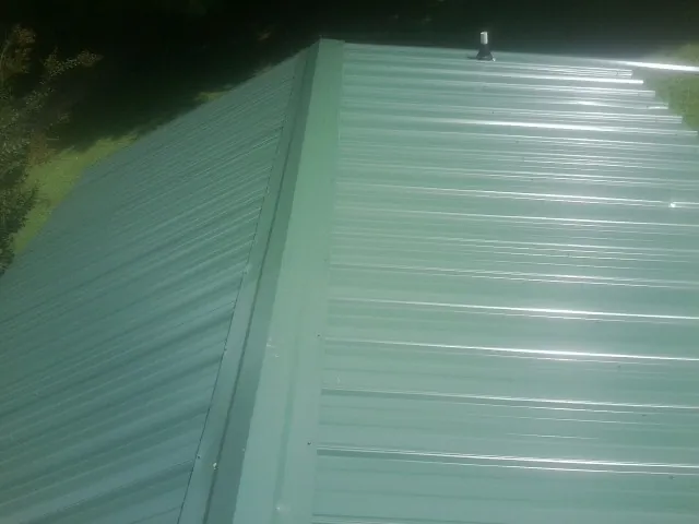 New green metal panels meeting at the ridge of a roof — Flat Roof Repair work by our crew in West Wardsboro