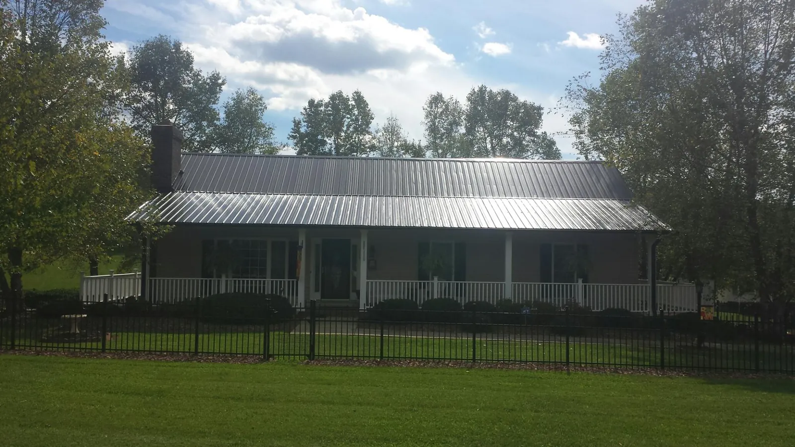 Gray metal roof on a brick ranch with a full width front porch — Gutter Guard Installation work by our crew in West Wardsboro