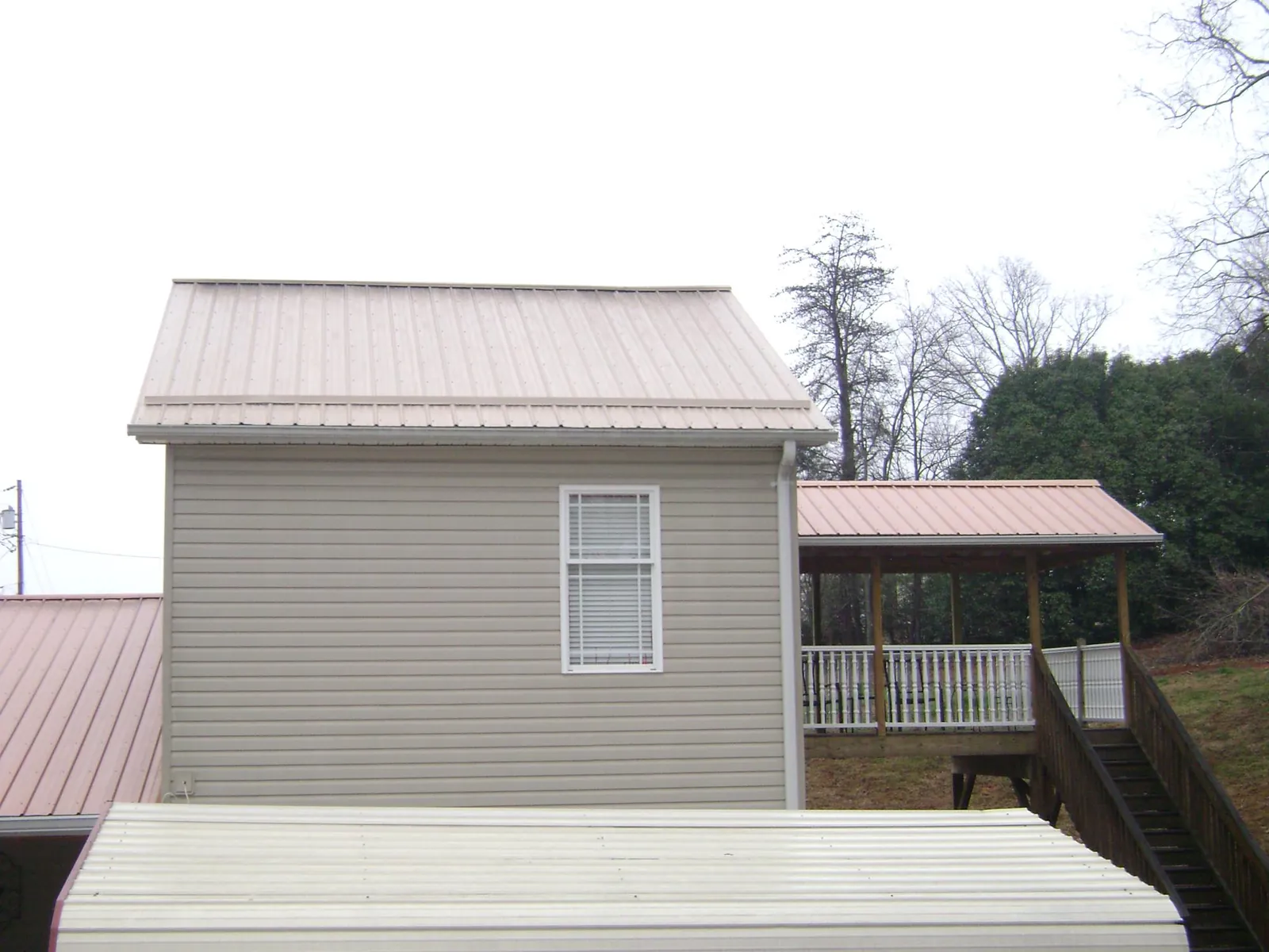 Tan metal roofs on a two story addition and attached porch, from a Roof Replacement job in West Wardsboro