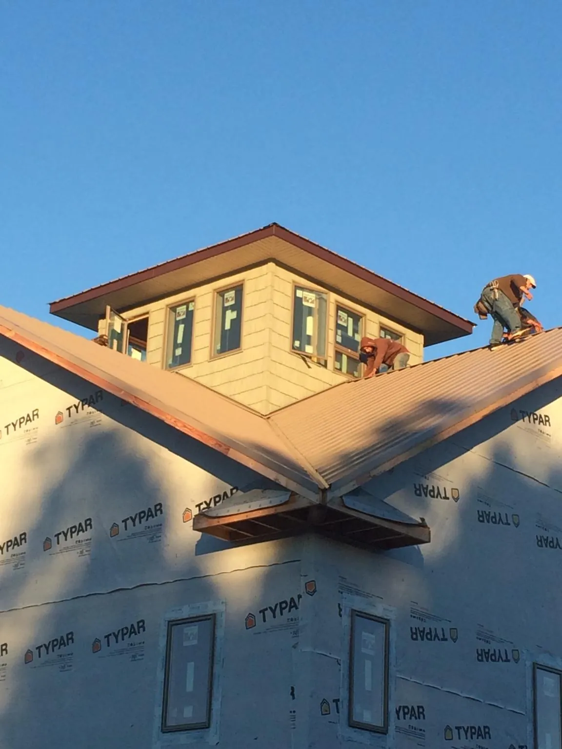 Roofers working around a rooftop cupola on a new metal roof at sunset — Roof Waterproofing in West Wardsboro by Roofing Brothers